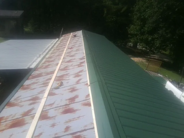 Old rusted panels beside newly installed green metal roofing — Wind Damage Roof Repair by Roofing Brothers in Corpus Christi