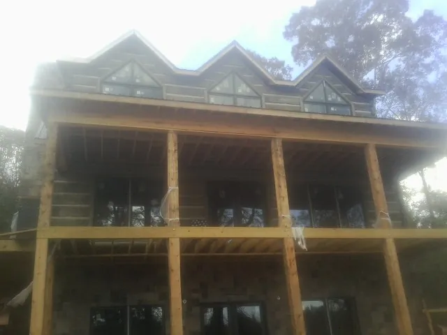 Dormers and porch framing on a large log home under construction — Roof Coating work by our crew in Corpus Christi
