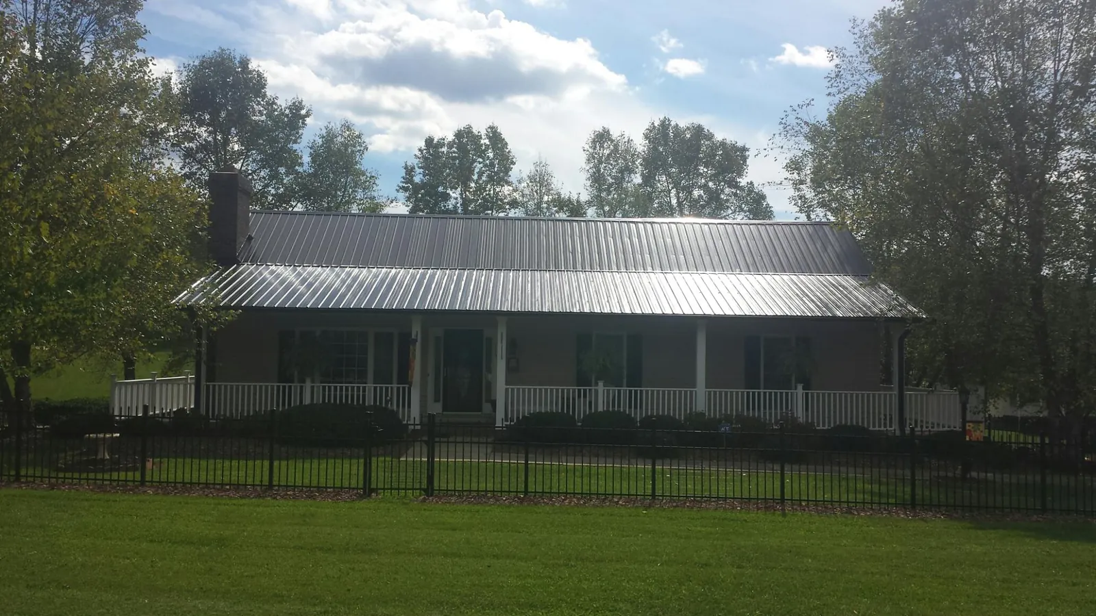 Gray metal roof on a brick ranch with a full width front porch — Gutter Guard Installation work by our crew in Corpus Christi