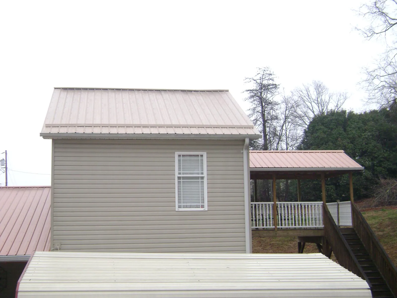 Tan metal roofs on a two story addition and attached porch, from a Roof Replacement job in Corpus Christi