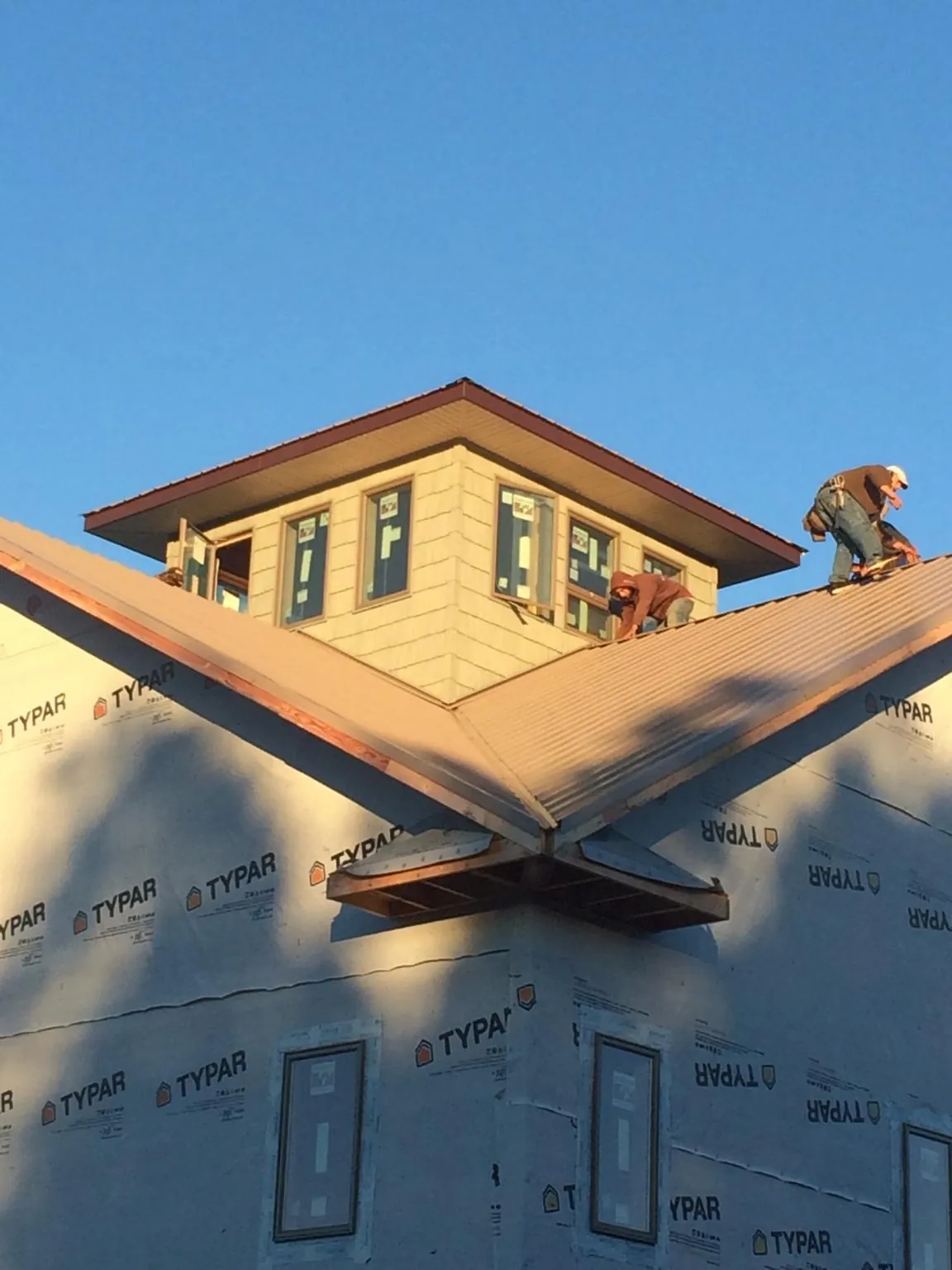 Roofers working around a rooftop cupola on a new metal roof at sunset — Roof Waterproofing in Corpus Christi by Roofing Brothers